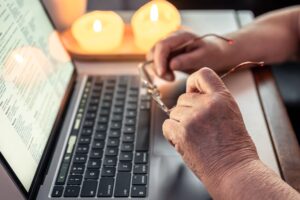 Retired woman uses laptop, hands close up.